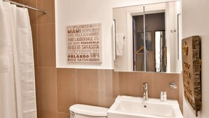A bathroom with a toilet, sink, and a mirror. A sign with Florida locations is visible on the wall. - ✨Cozy, compact studio Wynwood 1455R (Miami)