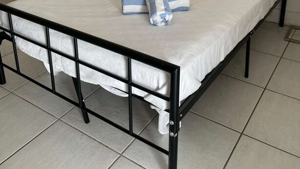 A neatly made bed with white linens and blue striped towels, a bedside lamp, and a tiled floor. - ✨Cozy, compact studio Wynwood 1455R (Miami)