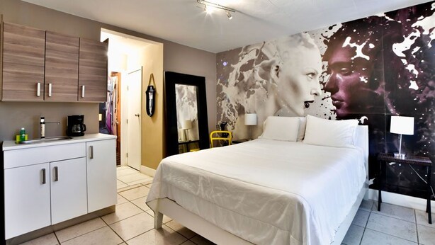 A bedroom with a bed, a desk, a chair, and a wall with a large abstract painting. - ✨Trendy/Stylish room in Wynwood 1455 (Miami)