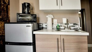 A compact kitchen with a stainless steel refrigerator, a coffee maker, and a sink with a modern faucet. - ✨Trendy/Stylish room in Wynwood 1455 (Miami)