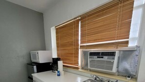 A compact kitchen with a built-in microwave, a sink, and a window with blinds. - ✨New, Trendy, Cool Wynwood Flat-12 (Miami)
