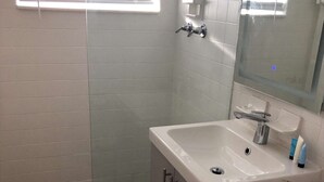 A bathroom with a glass-enclosed shower, a white sink, and a toilet.