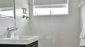 A bathroom with a white sink, dark cabinet, and a window above the shower. - ✨Designer Chick Flat w/Full Kitchen (Miami)