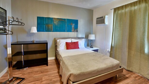 A hotel room with a bed, bedside tables, a desk, and a wall-mounted air conditioner. - ✨Bright amazing studio in Wynwood (Miami)