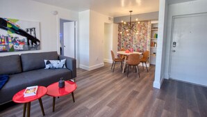 Een moderne woonkamer met een grijze bank, rode bijzettafels en een stadsmuur.