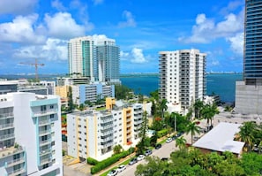 A high-rise building with a view of the ocean, surrounded by other buildings and palm trees.