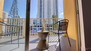 Un balcón con una silla y una mesa pequeña, con vistas a un edificio alto y árboles.