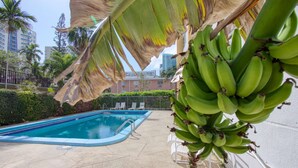 Una piscina con una palmera y un racimo de plátanos al frente.