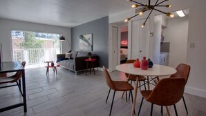A modern living room with a grey sofa, a round dining table with chairs, and a unique ceiling light fixture. - Amazing Renovated One Bedroom w/Free Parking and Pool with Balcony (Miami)