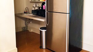 A compact kitchen with a stainless steel refrigerator, a microwave, and a sink. - Marie Celeste Creole Country Cottage (Destrehan)
