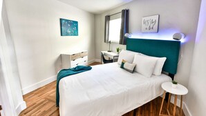 A modern bedroom with a bed, bedside table, desk, and a painting on the wall. - ✨Rest + EAT + SHOP | NEW ONE BEDROOM PLUS FREE PARKING (Miami)