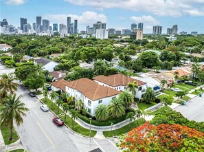 A residential area with a white building featuring a red-tiled roof, surrounded by lush greenery and palm trees. - ✨ New Studio plus FREE parking fee (Miami)