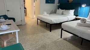 A hotel room with two beds, a table with a chair, a desk, a mirror, and a painting on the wall. - ✨New Studio plus FREE Parking (Miami)