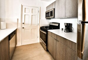 Compact kitchen with a minimalist design, featuring a gas stove, microwave, and coffee maker.