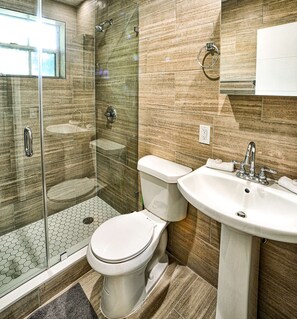 Bathroom features a glass-enclosed shower, toilet, and sink.