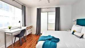 Een moderne slaapkamer met een bed, bureau en stoel.