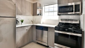 Een moderne keuken met roestvrijstalen apparatuur, houten kastjes en een raam dat zorgt voor natuurlijk licht.