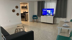 A compact living space with a kitchenette, a TV, and a dining area.