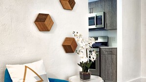 A modern living room with a blue armchair, a white side table with a potted orchid, and wooden hexagonal wall decorations.