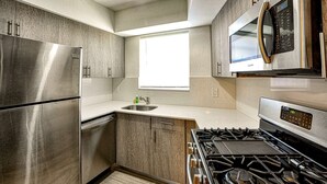 A modern kitchen with stainless steel appliances, a built-in microwave, and a window providing natural light.