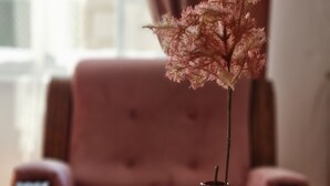A vase with a dried flower arrangement on a white table in a room with a pink armchair and a small table lamp. - Old bridge (Mostar)