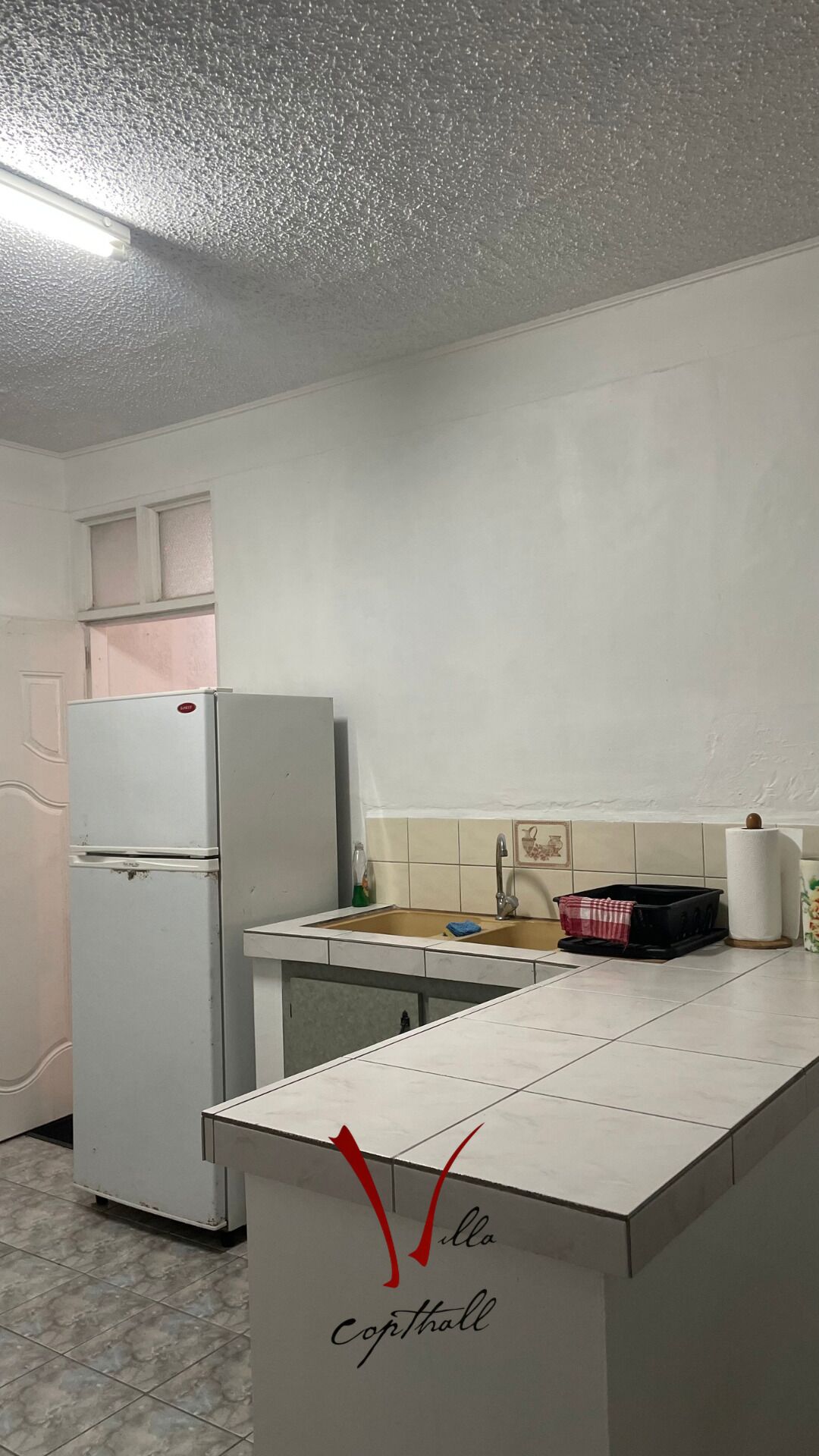 Una cocina con un refrigerador blanco, un lavamanos y un salpicadero de azulejos.