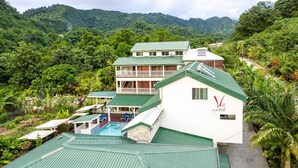 A hotel with a pool, surrounded by lush greenery and mountains.