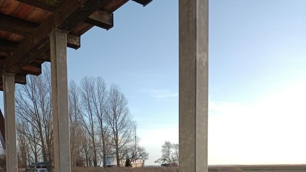A covered outdoor area with a view of a river and distant buildings. - Aalhaus Wustrow apartment to the meadow 900 m to the beach (Wustrow)