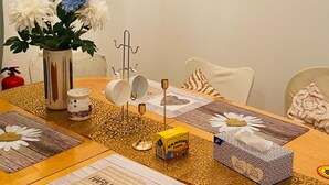 Een eettafel met een bloevas, een lijst met een schilderij en een tafelkleed met een hartmotief.