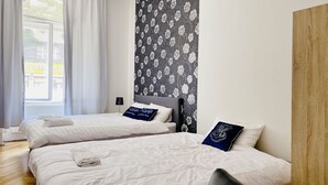 Een hotelkamer met twee bedden, witte beddengoed en een wand met bloemenprint.