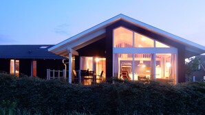 A modern house with a large glass front, a covered patio, and a sloped roof. - Wooden holiday home "Feldrain" on the Baltic Sea - Sauna - 500m to the Baltic Sea beach - Wlan (Zierow)