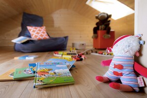 A cozy room with a wooden floor, a bean bag chair, a plush toy, and children's books.