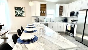 A modern kitchen with white cabinetry, a marble countertop, and stainless steel appliances. - Brand new home, 1 block from Beach (Gulfport)