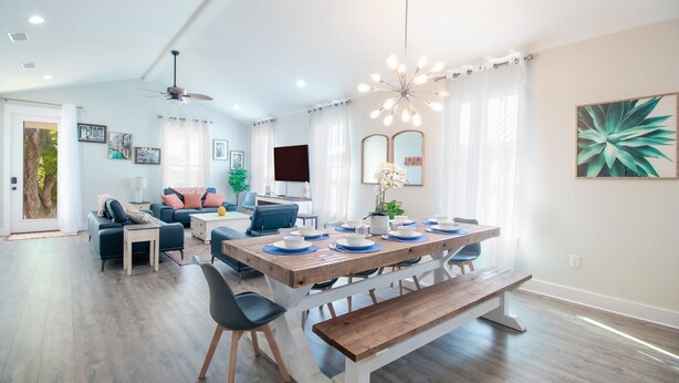 A spacious living room with a large wooden dining table, comfortable seating, and a ceiling fan. - Brand new home, 1 block from Beach (Gulfport)
