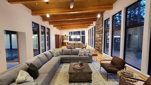 A spacious living area with a large sectional sofa, a coffee table, and a dining table in the background. - Amazing New 5 Bed Home next to the Columbia River. Sleeps 10 adults & 6 Kids (Stevenson)