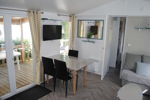 A room with a glass table, black chairs, a TV, a mirror, and a sofa.