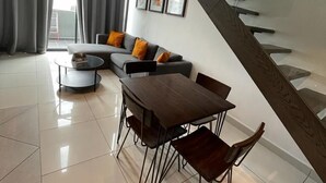 Una sala de estar moderna con comedor, una escalera y vistas al exterior.