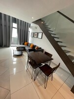 Un soggiorno moderno con zona pranzo, una scala e vista all'esterno.
