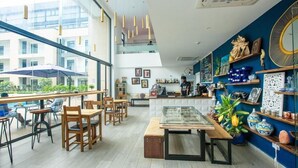 Un café moderno con mobiliario de madera, un expositor de vidrio y objetos decorativos en estantes.