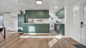 A modern kitchen with green cabinets, a central island, and a dining area with a table and chairs.