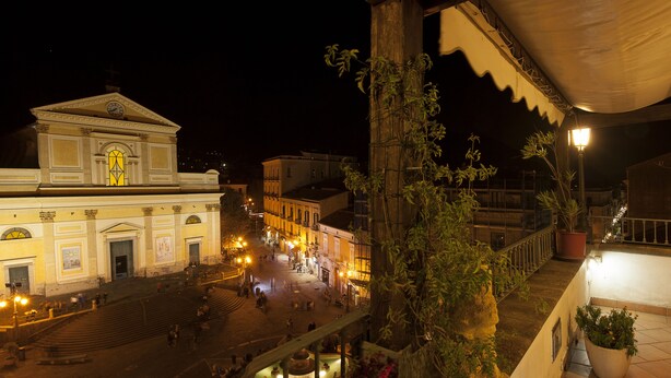A historic building with a central dome and a large arched entrance, surrounded by a cobblestone square with street lamps and potted plants. - b&b l'Incanto (Cava de' Tirreni)