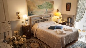 A neatly arranged bedroom with a bed, bedside lamps, a nightstand, a chair, and a painting on the wall. - b&b l'Incanto (Cava de' Tirreni)