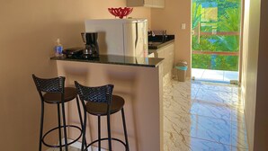 Cozinha compacta com geladeira, cafeteira e dois banquetas.