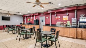 A restaurant with multiple tables and chairs, ceiling fans, a kitchen area, and a television mounted on the wall. - MainStay Suites Ozona I-10 (Ozona)