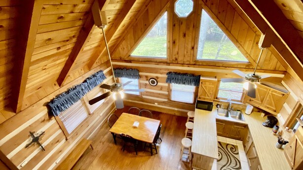 A wooden cabin with a dining area, kitchen, and two large windows. - Log Cabin, walk to National park trails and minutes from Gatlinburg with a view! (Townsend)