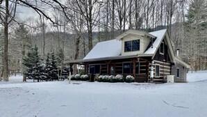 A log cabin with a snow-covered roof, surrounded by a forest. - Log Cabin, walk to National park trails and minutes from Gatlinburg with a view! (Townsend)