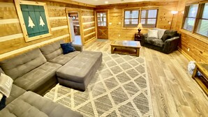A cozy log cabin interior with a sectional sofa, a coffee table, and a fireplace. - Log Cabin, walk to National park trails and minutes from Gatlinburg with a view! (Townsend)