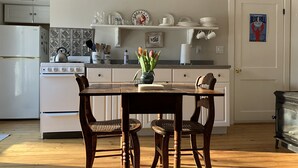 Een keuken met een houten tafel, stoelen, een fornuis en een koelkast.