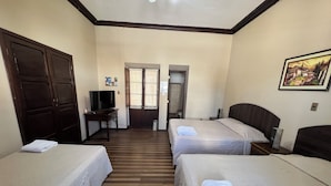 Habitación de hotel con dos camas, un escritorio, televisión y puerta que da a un baño.
