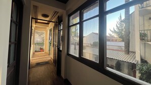 Un pasillo con amplias ventanas, suelo de madera y vistas a edificios.